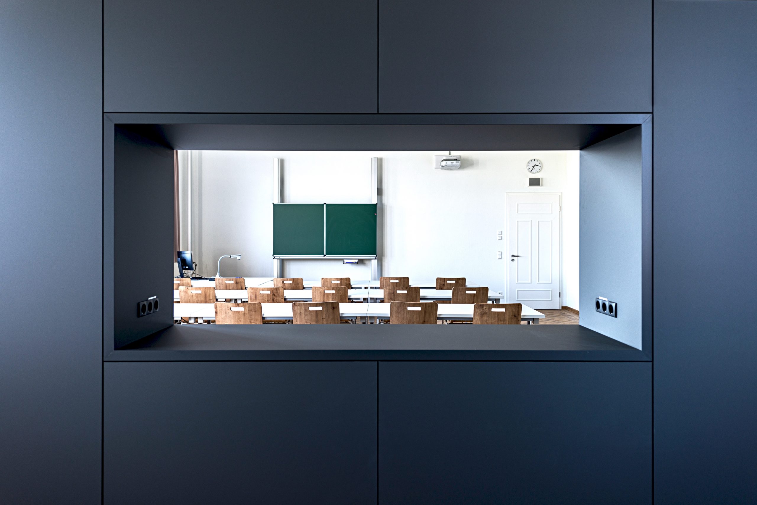 Blick vom Nebenraum durch eine große Öffnung im Schrank in das Klassenzimmer der Fachakademie für Sozialpädagogik Furth im Wald.