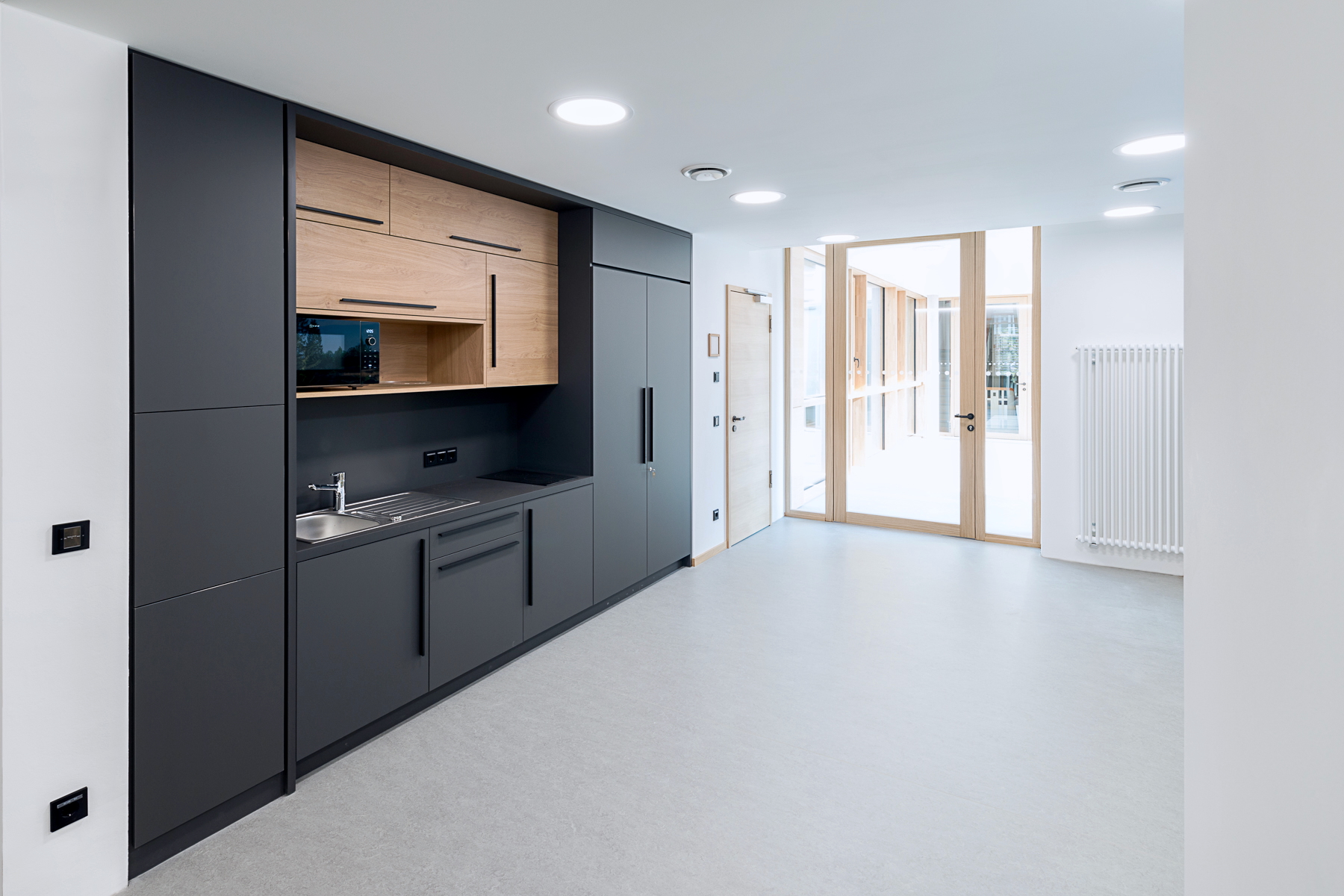 Teeküche im Finanzamt Waldmünchen, Außenstelle des Finanzamts Erlangen, am Übergang zum denkmalgeschützten Altbau mit beidseitiger Verglasung und lichtdurchflutetem Aufenthaltsbereich.