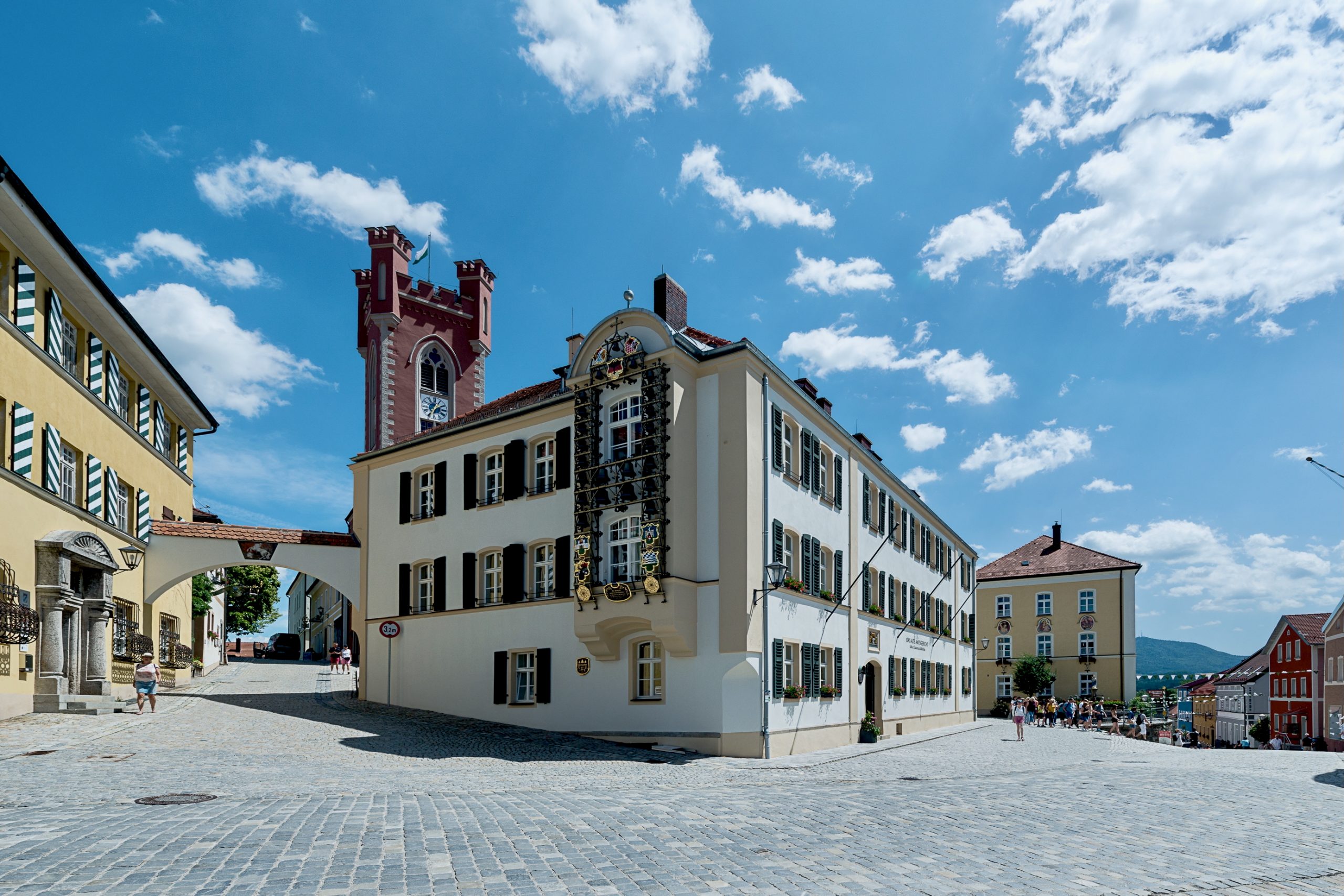 Außenaufnahme des Alten Amtsgerichts Furth im Wald vom Stadtplatz mit historischem Glockenspiel an der Nordfassade und dem Stadtturm im Hintergrund.