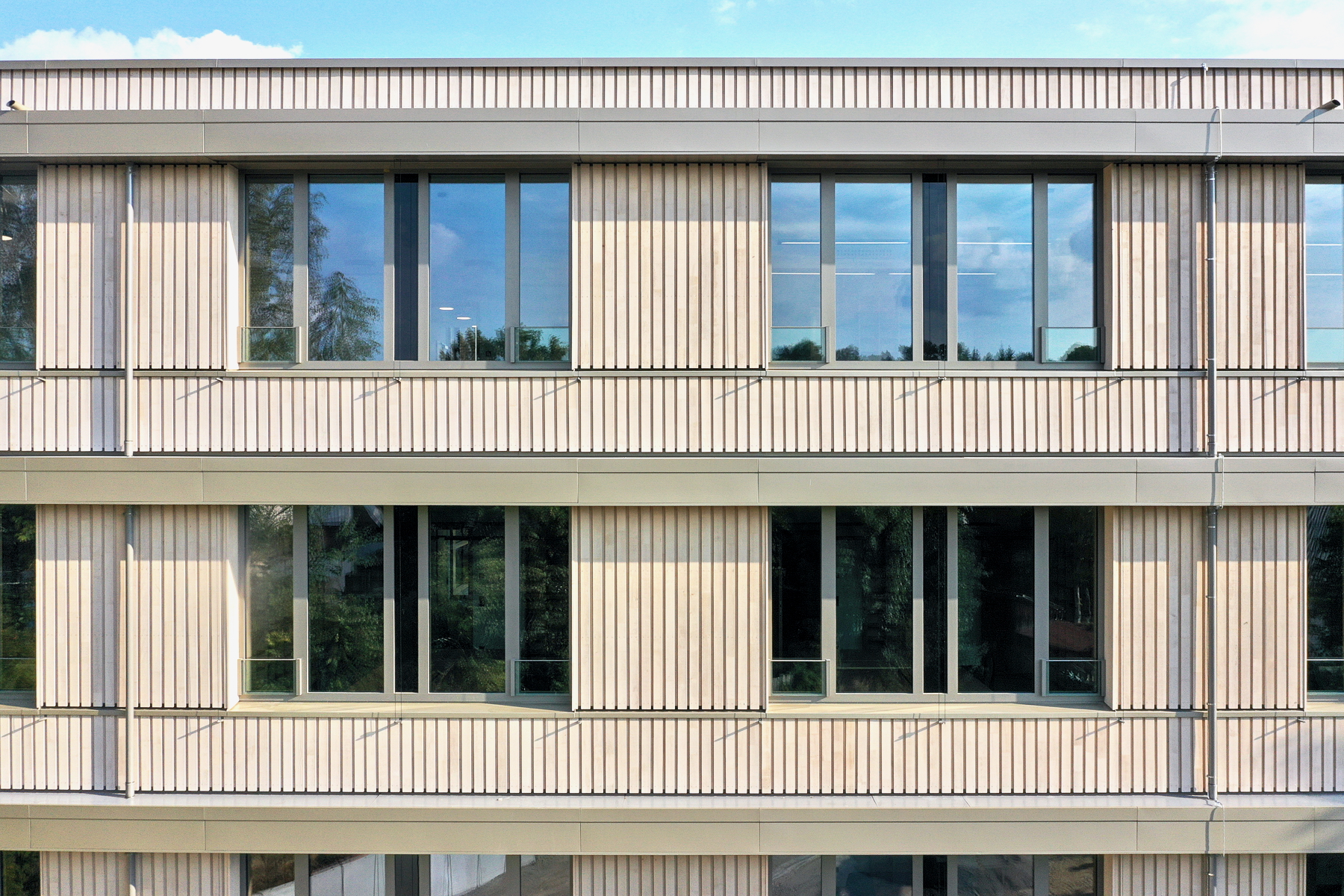 Fassadendetail des Finanzamts Waldmünchen, Außenstelle des Finanzamts Erlangen, mit zwei Büroachsen im 1. und 2. Obergeschoss, Hybridbauweise aus Stahlbetonskelett und Holzaußenwänden, Holzfassade im Passivhausstandard.