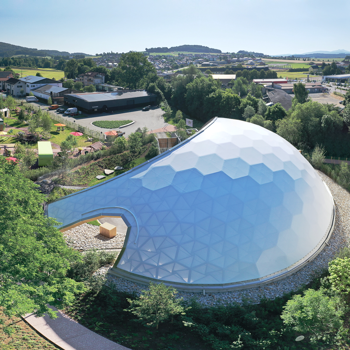 Drohnenaufnahme der Park-Arena Furth im Wald von Südwesten mit sichtbarer Wabenstruktur, innovativer Holzkonstruktion unter lichtdurchlässiger Membran und Blick zur Drachenhöhle während der Landesgartenschau 2025.