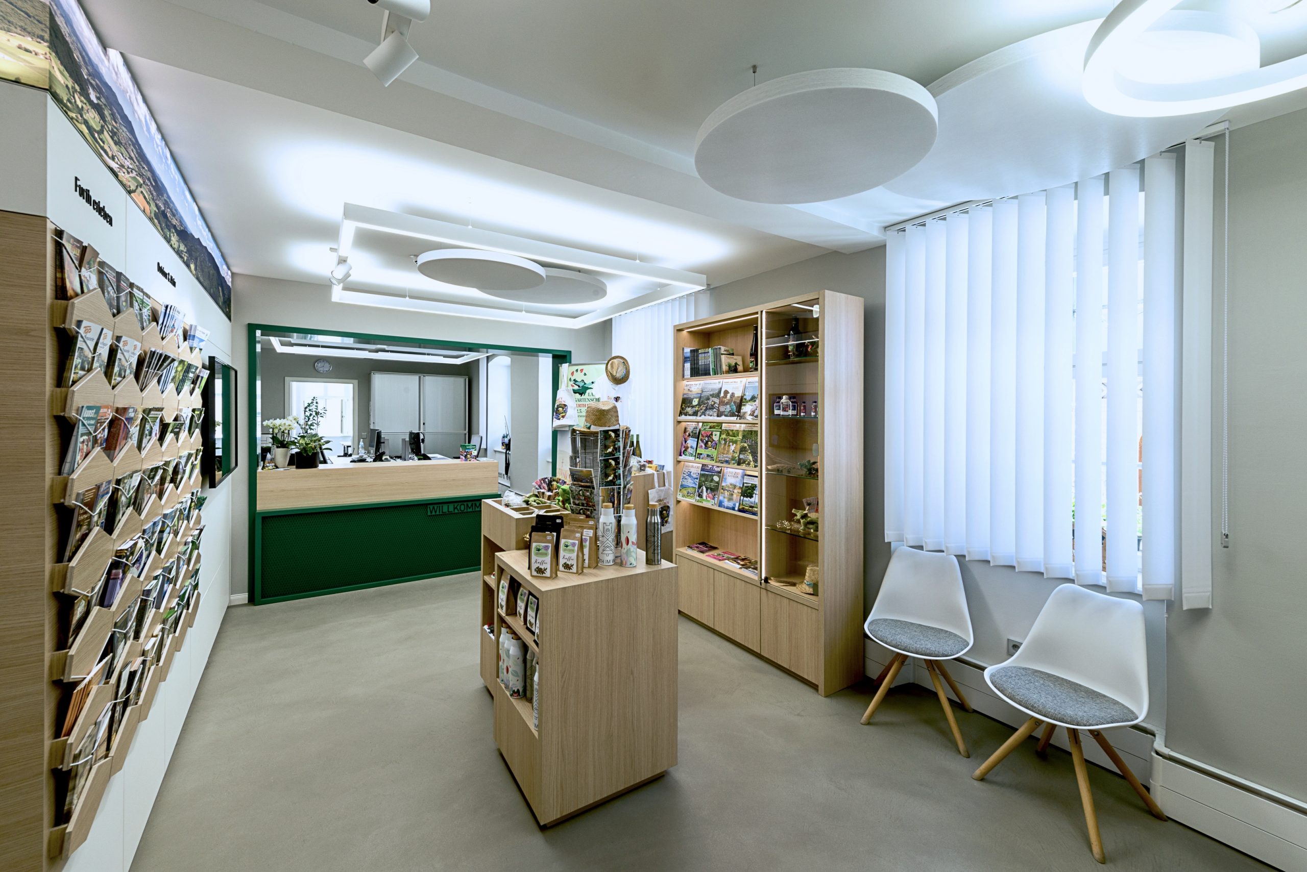 Innenaufnahme der Touristinformation im Erdgeschoss des Alten Amtsgerichts in Furth im Wald. Der zentrale Tresen bildet den Empfangsbereich, dahinter schließen die Büros an. Die Gestaltung verbindet die historische Bausubstanz mit einer klaren, funktionalen Raumanordnung, die den Anforderungen einer modernen Nutzung gerecht wird.