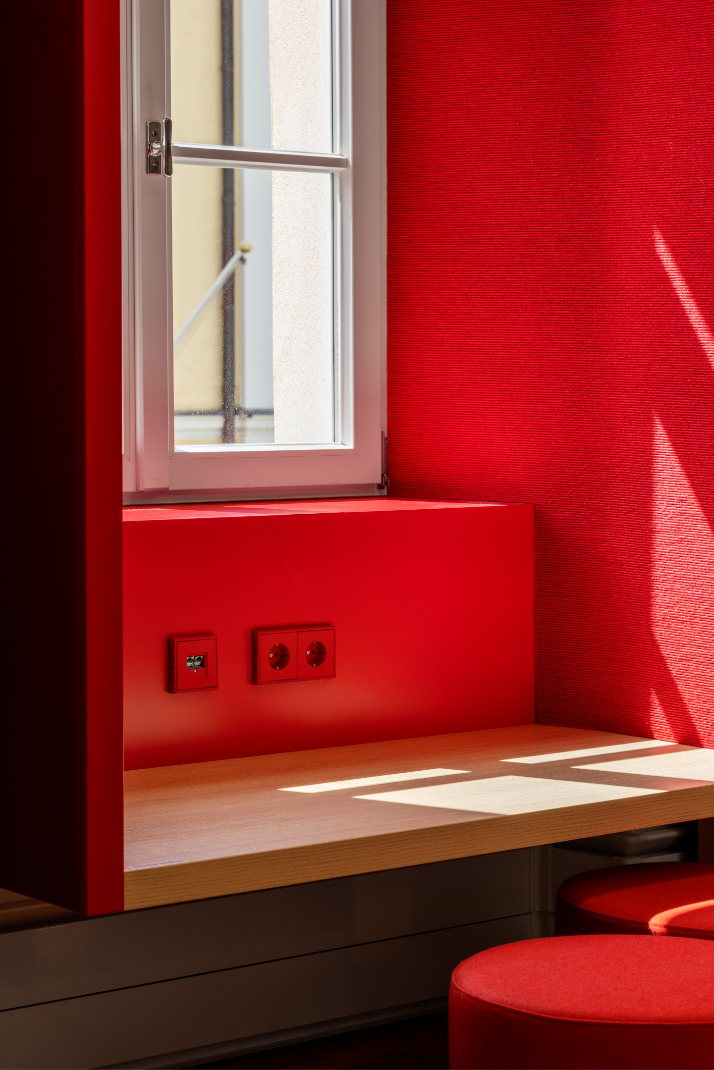 Historisches Holzfenster im Alten Amtsgericht Furth im Wald mit akustisch wirksamer Leibungsverkleidung und integriertem Kindertisch mit Sitzhockern.