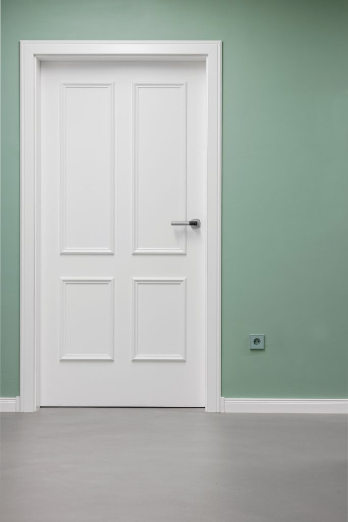 Neue weiße Tür mit Kassettenfüllung im Alten Amtsgericht Furth im Wald, eingebaut in eine grün gestrichene Wand, passend zum restaurierten Farbkonzept.